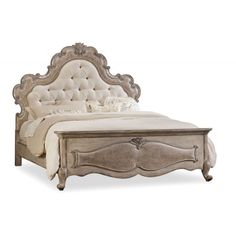 an antique style bed with white linens and tufted headboard, made from wood