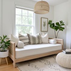 a living room with a couch, coffee table and potted plants on the windowsill