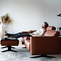 a man sitting in a recliner chair with headphones on and his feet up