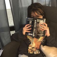 a woman is holding up a book to her face