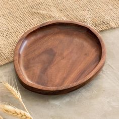 a wooden plate sitting on top of a table next to some ears of wheat and burl