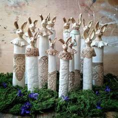 four white vases with rabbits on them and blue flowers in the grass around them