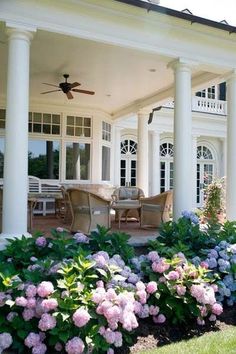 a large white house with columns and flowers in the front yard