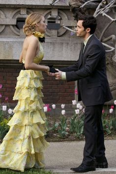 a man in a suit and tie standing next to a woman in a yellow dress