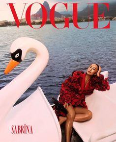 a woman in a red dress is sitting on a swan boat with the cover of a magazine