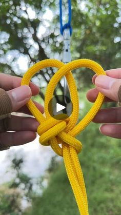 two hands holding a yellow rope in the shape of a heart