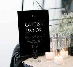 a table with candles and a sign that says guest book next to some glasses on it