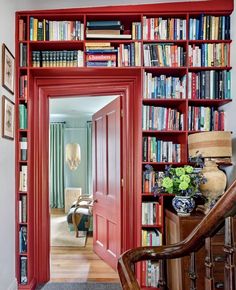 a red bookcase filled with lots of books in a living room next to a doorway