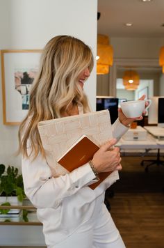 a woman holding a cup and folder in an office