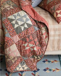 a bed covered in a colorful quilt and pillows