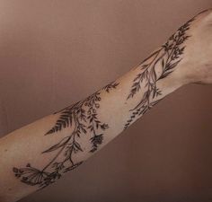 a woman's arm with flowers and leaves tattooed on the arm, in black ink