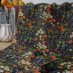 an image of a flowered blanket on a couch with vases and flowers in the background