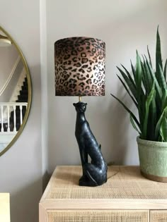 a black cat lamp sitting on top of a table next to a potted plant