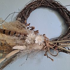 a dried wreath with white flowers and feathers