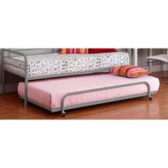 a metal day bed with pink sheets and pillows