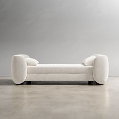 a white couch sitting on top of a floor next to a gray wall and chair