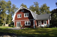 a red house with white trim and windows on the front, surrounded by green grass