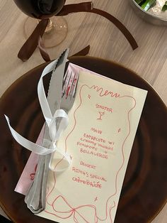 a plate with a menu on it next to a glass of wine and a fork