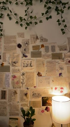 a lamp sitting on top of a table next to a wall covered in pictures and plants