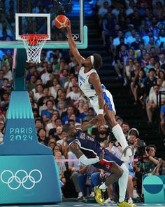 a basketball player dunks the ball in front of an audience at a sporting event