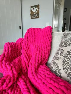 a bright pink blanket is draped over a couch