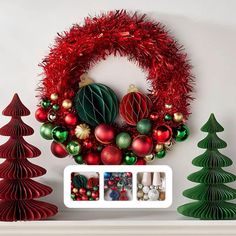 a christmas wreath with red and green ornaments hanging on the wall next to other holiday decorations