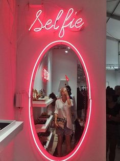 a woman standing in front of a pink neon sign