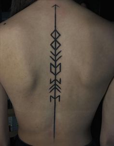 the back of a woman's upper body with an arrow tattoo