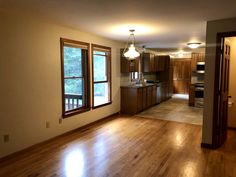 an empty living room and kitchen with hard wood flooring in the middle of it