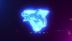 two neon signs that are on the side of a building in the dark, one with a shark