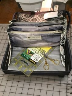 an open suitcase sitting on top of a tiled floor next to a ruler and scissors