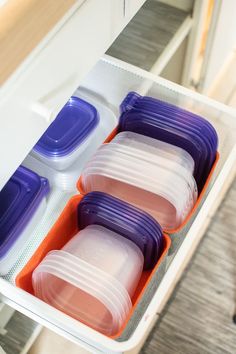 three containers in an orange and purple container on a white shelf next to another container