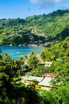 a tropical island with lots of trees and houses on the hillsides in the foreground