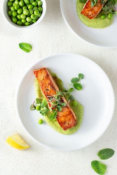 two white plates topped with food next to peas