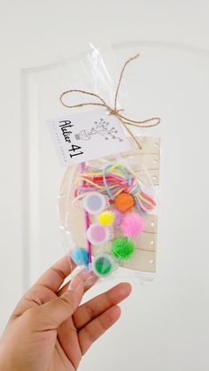 a hand holding a package of colorful pom poms