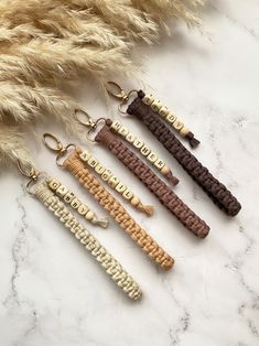 four keychains with the word love spelled in gold, brown, and white