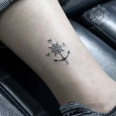 a woman's foot with a small anchor tattoo on her left leg and an arrow in the middle