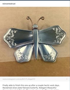 a silver butterfly brooch sitting on top of a cardboard box with the caption below it