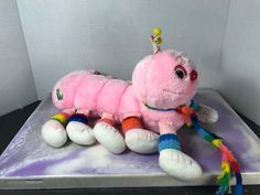 a pink stuffed animal laying on top of a purple surface