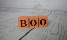 an orange block spelling boo on top of a wooden table