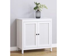 a white cabinet with two doors and a vase on top