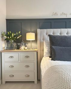 a white bed sitting next to a night stand with a lamp on top of it