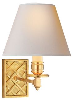 a gold wall light with a white shade on the top and bottom part of it