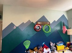 there is a room with toys on the floor and mountains painted on the wall behind it