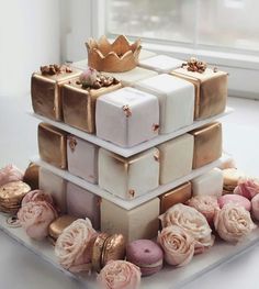 a three tiered cake decorated with pink roses and gold wrapped presents on a white table