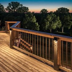 the deck is lit up at night with lights on and trees in the distance behind it