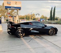 a black sports car parked in front of a gas station with no one around it