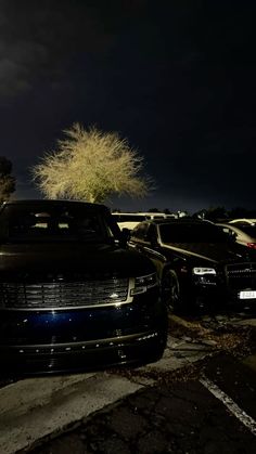 two cars parked next to each other in a parking lot at night with the lights on