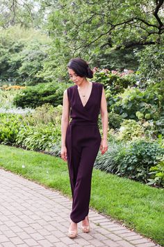 a woman in a purple jumpsuit walking down a sidewalk