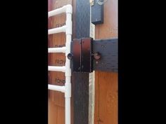 a wooden fence with an iron gate and white pipes attached to the side of it